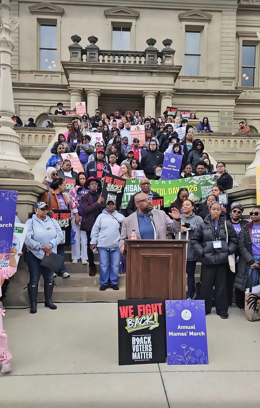 Kermit Williams speaking at a podium on the Michigan Capitol steps in front of a large crowd