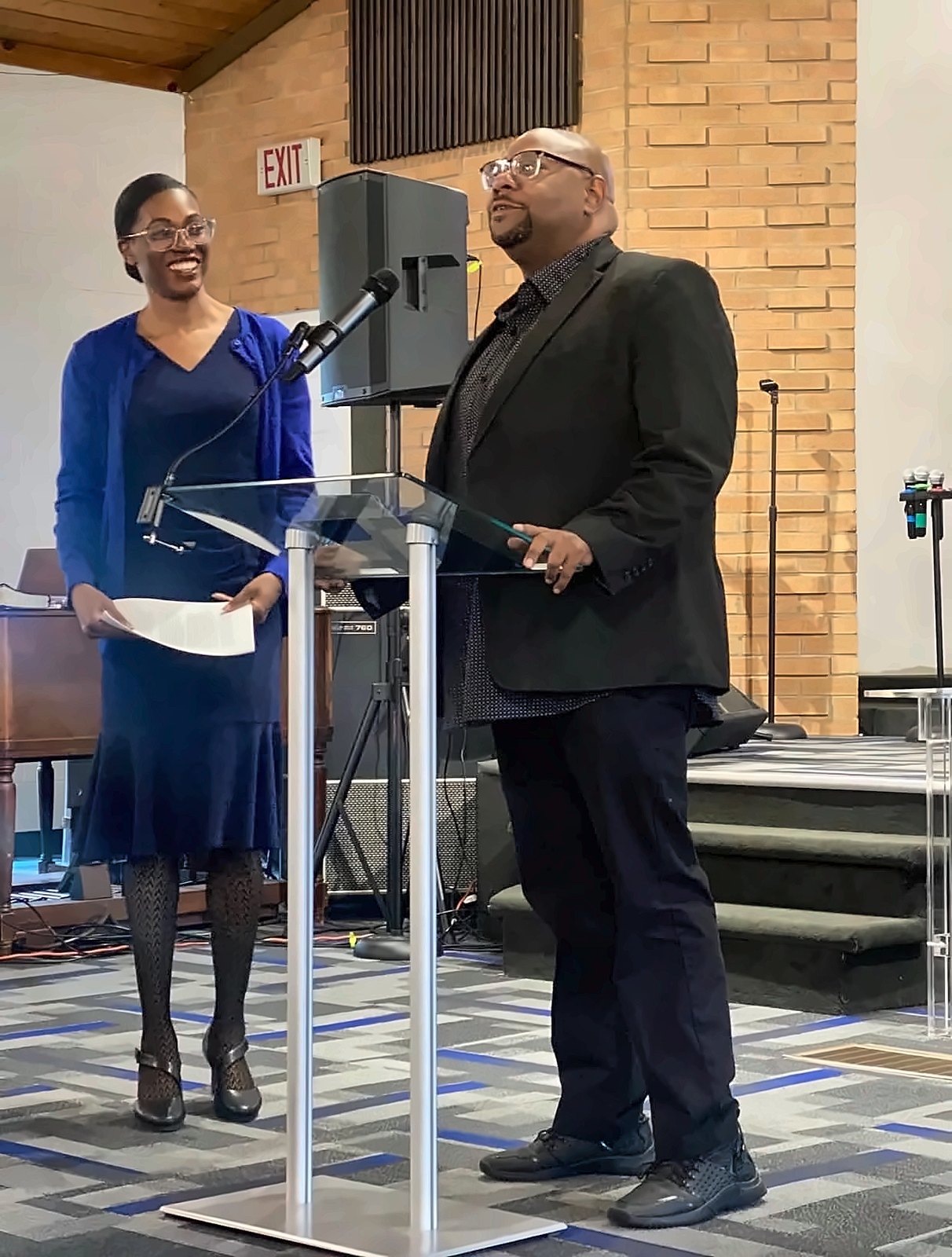 Kermit Williams speaking at a podium beside a program host