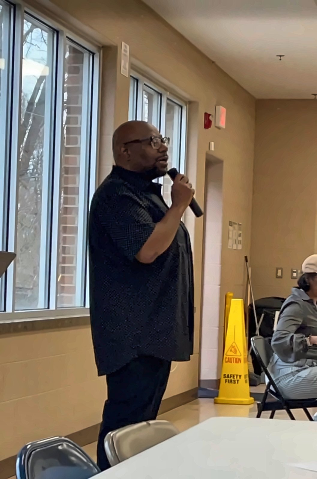 Kermit Williams speaking with a microphone at a community meeting