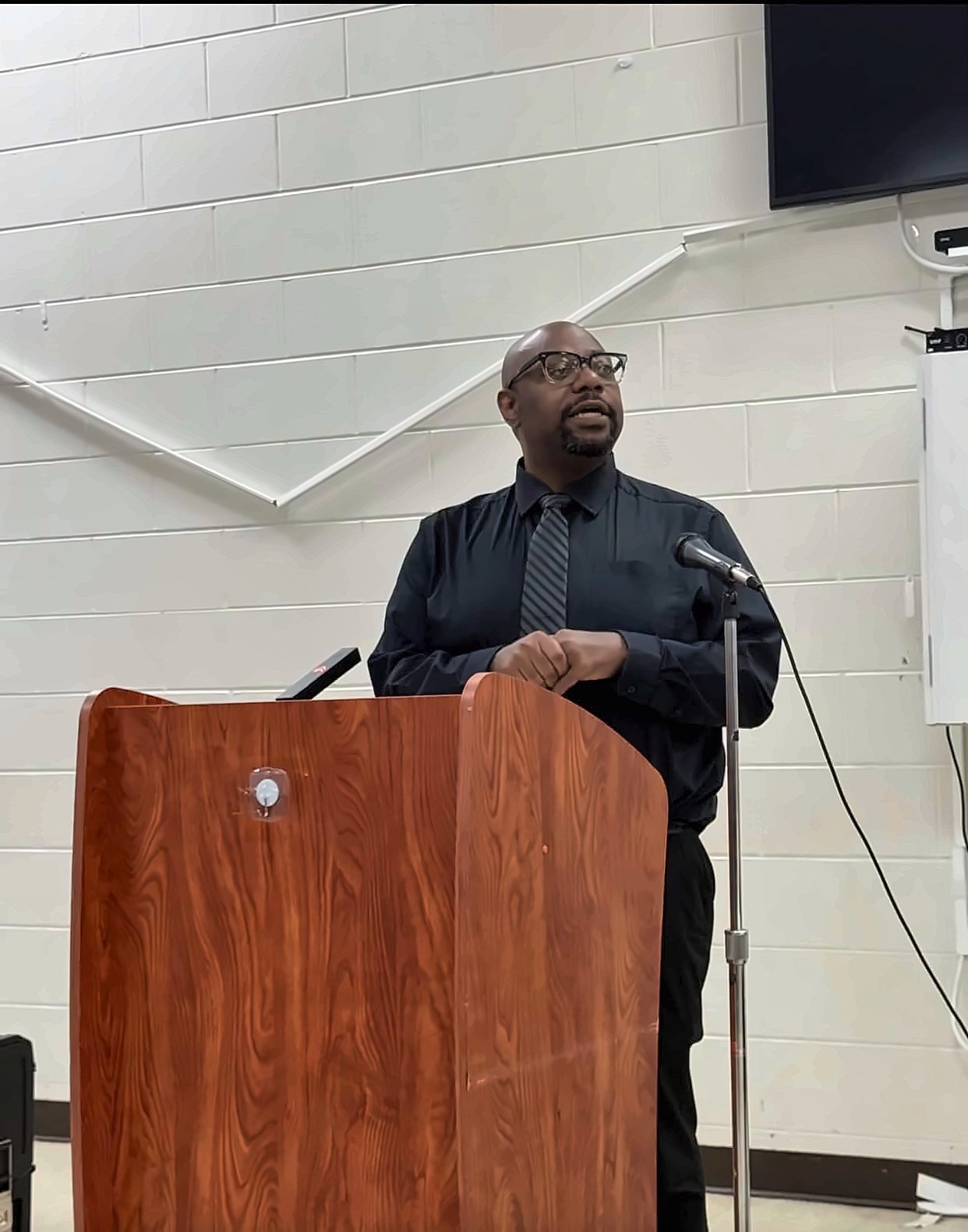 Kermit Williams speaking at a podium in a community center