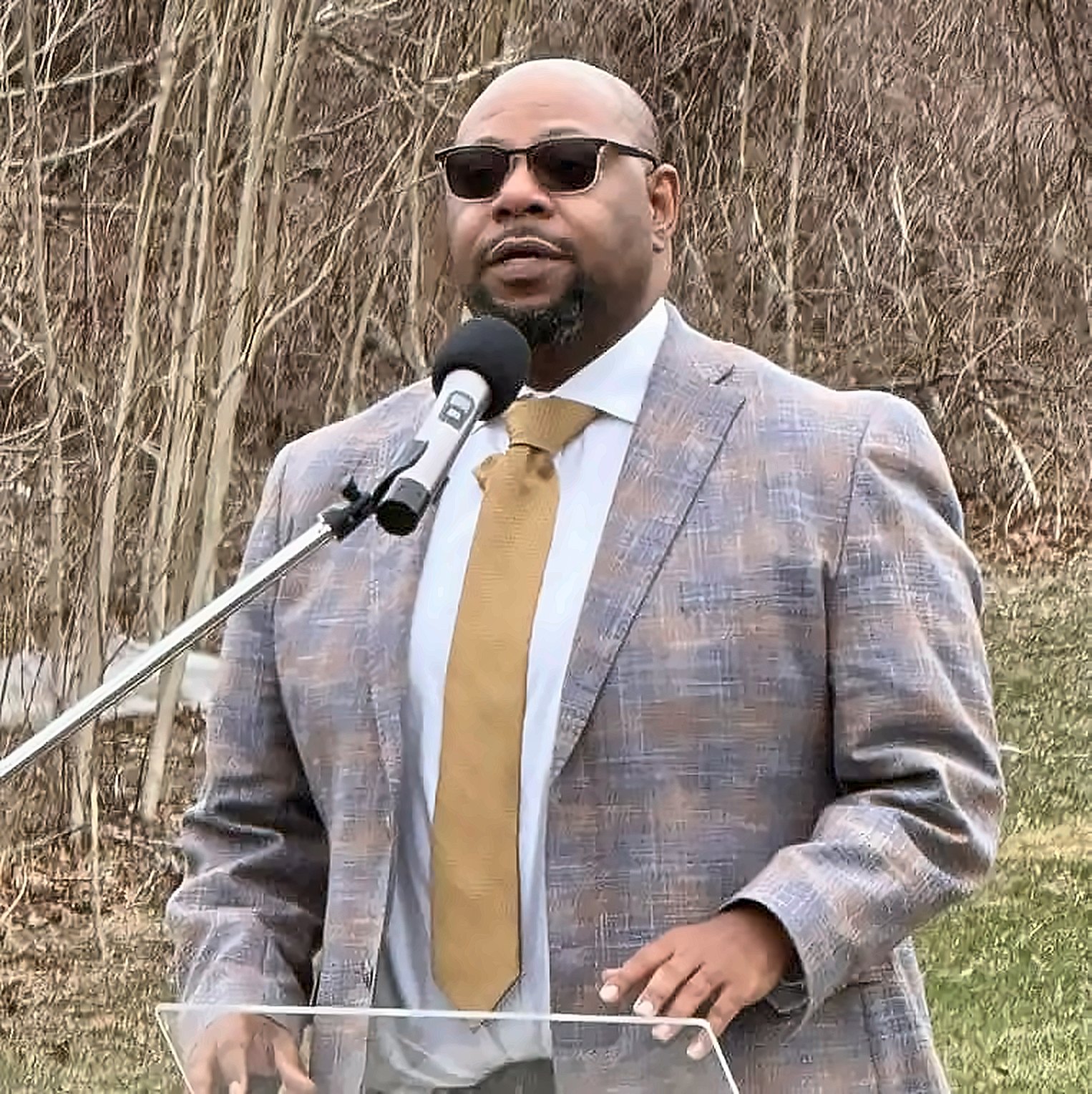Kermit Williams speaking at a microphone at an outdoor social justice event
