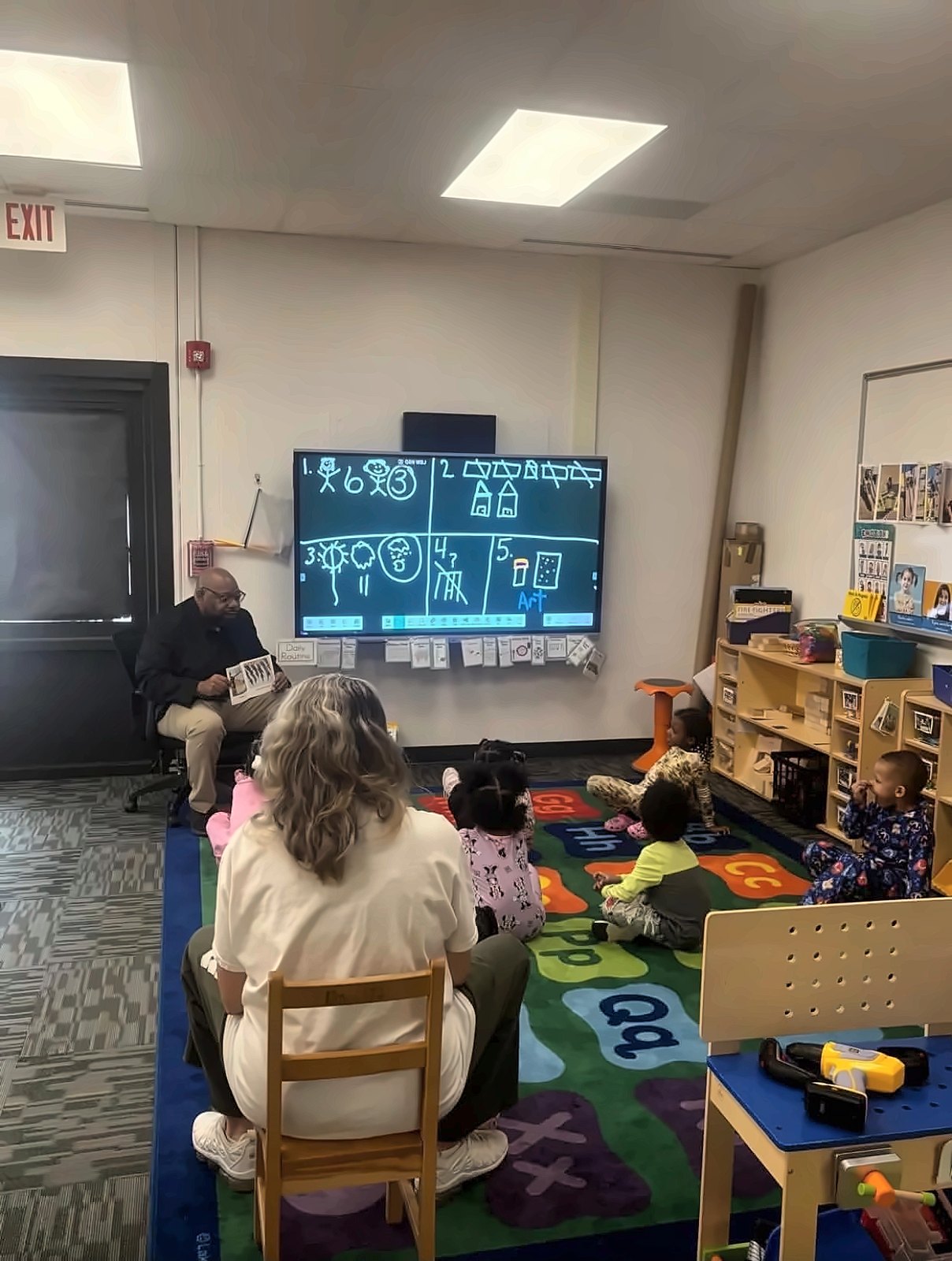 Kermit Williams reading a book to preschool children in a classroom